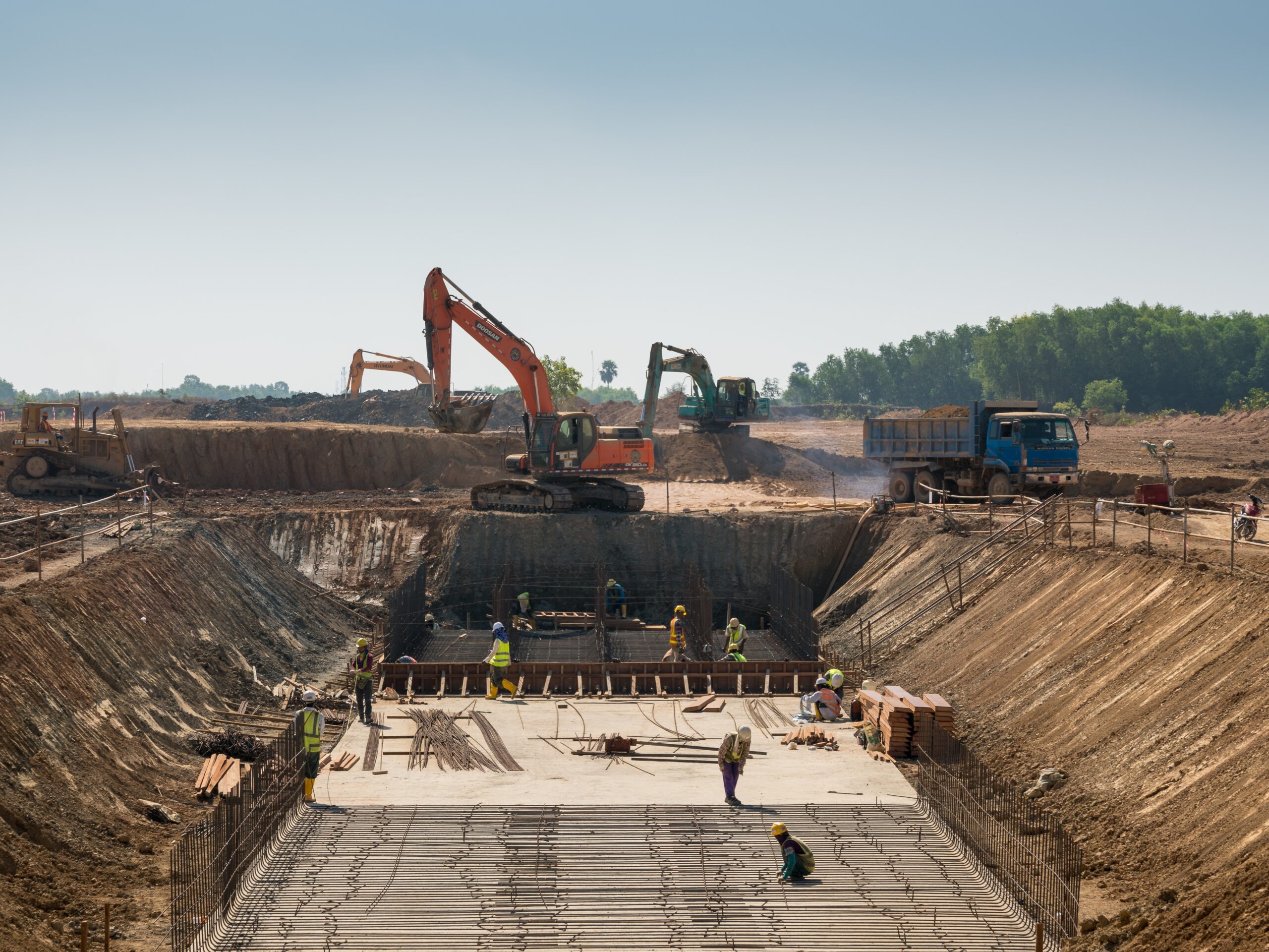 A close shot of heavy machines and construction workers working on a building